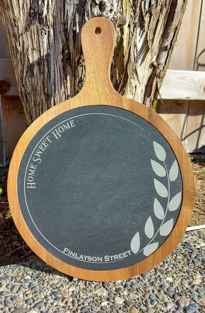 Round chalkboard sign with decorative leaf design and text.