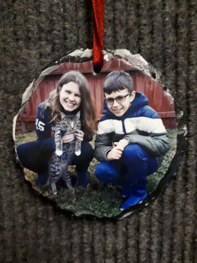 Two children crouching outdoors, smiling with a small animal.