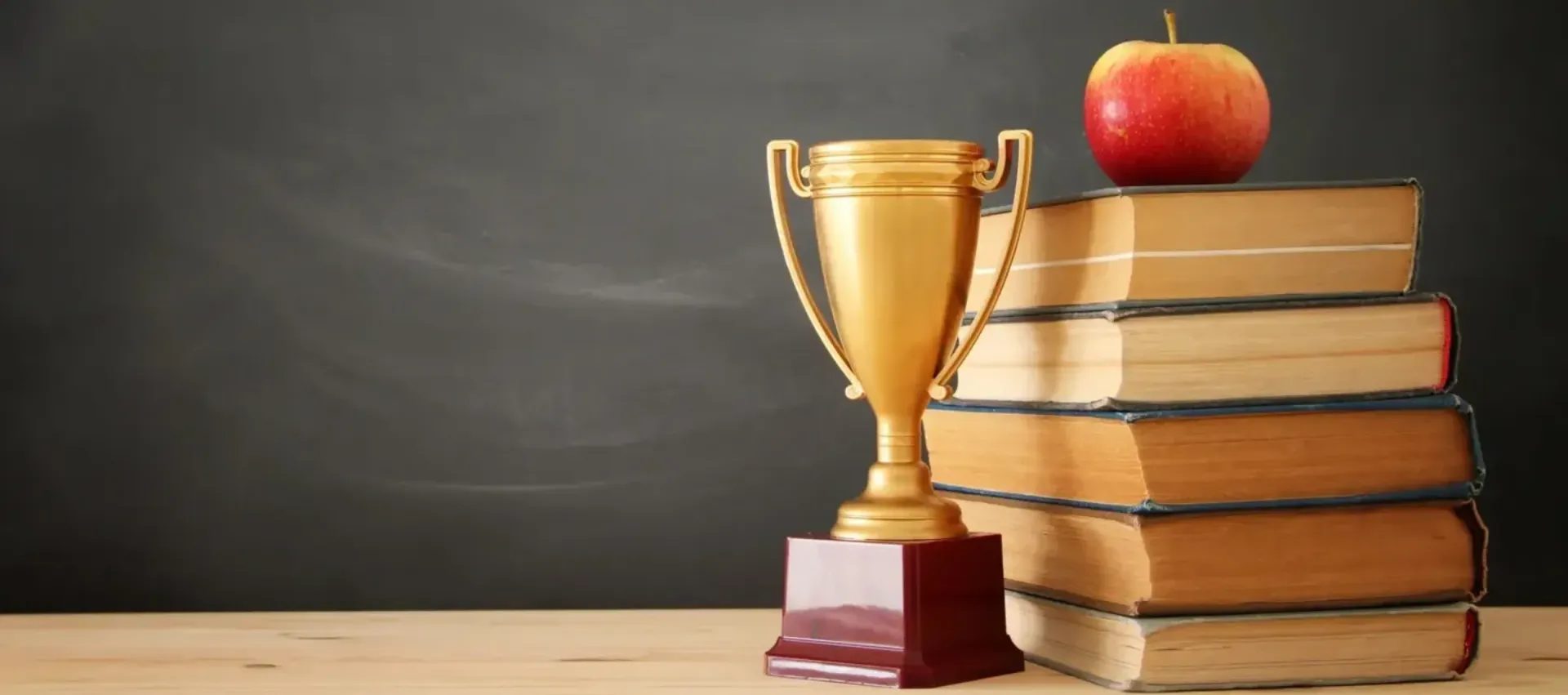 Golden trophy on a wooden base against a dark background.
